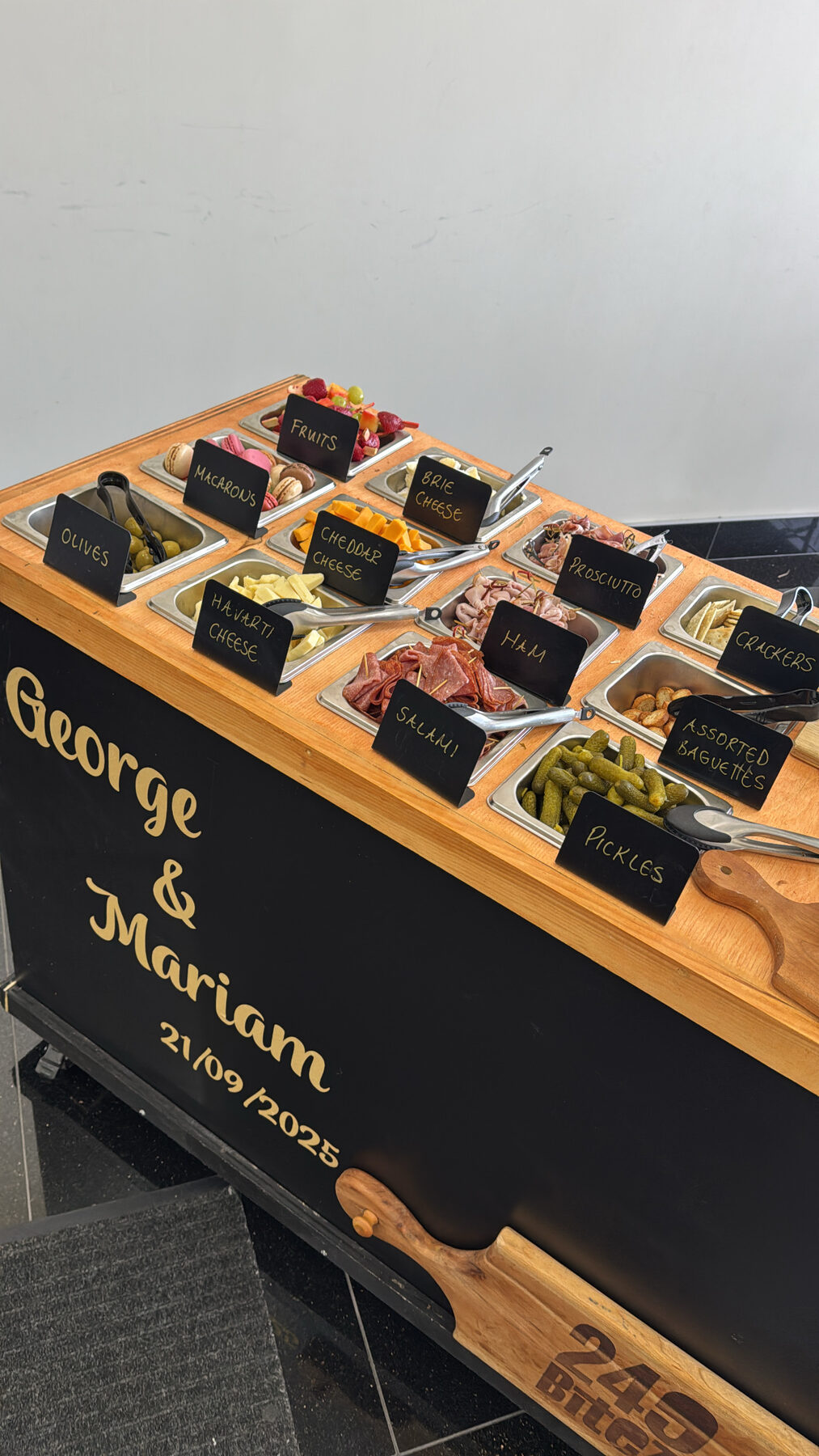 The 249 Bitez charcuterie cart lettered in gold for a wedding, with labelled trays of cheese, cured meats, and macarons.