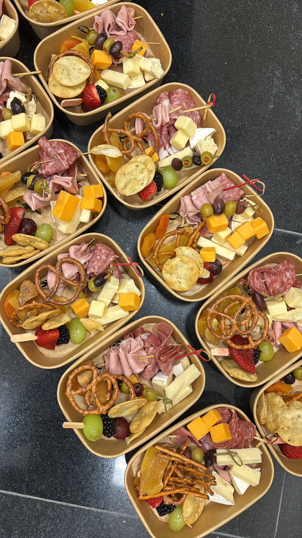 Charcuterie boxes with skewers, macarons, and fresh fruit.