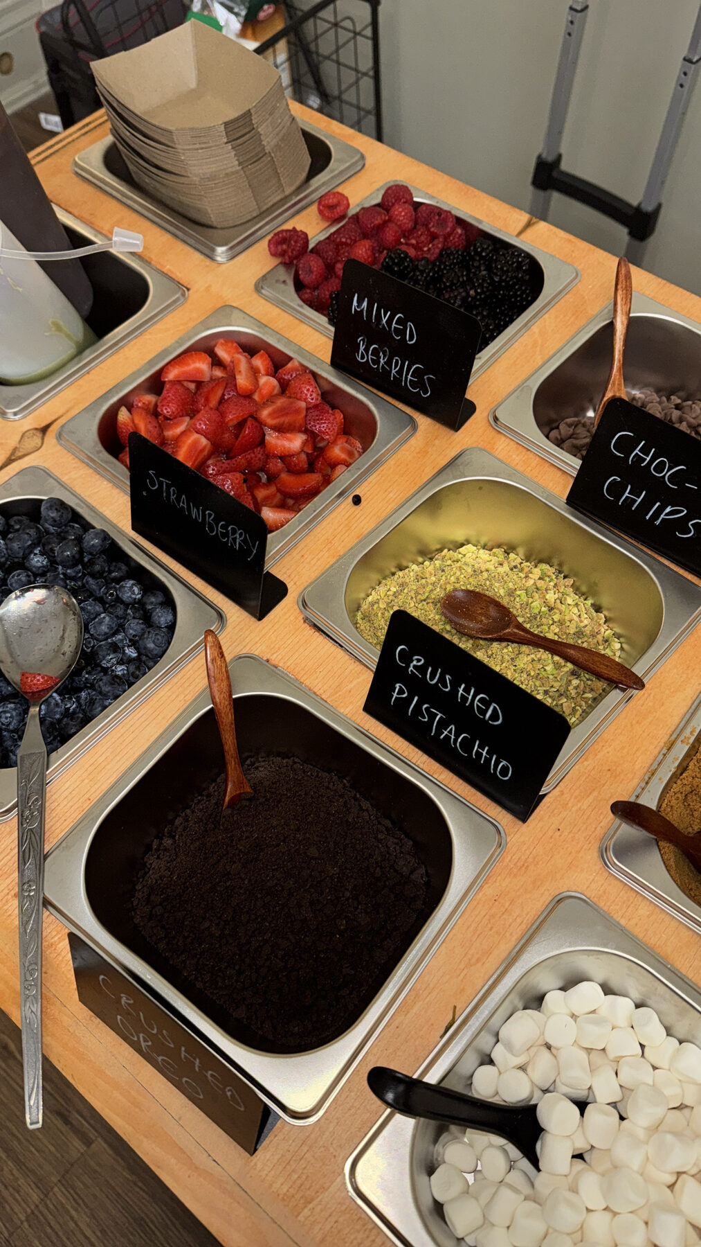 Chalk-labelled waffle toppings — berries, crushed pistachio, Oreo, and choc chips.