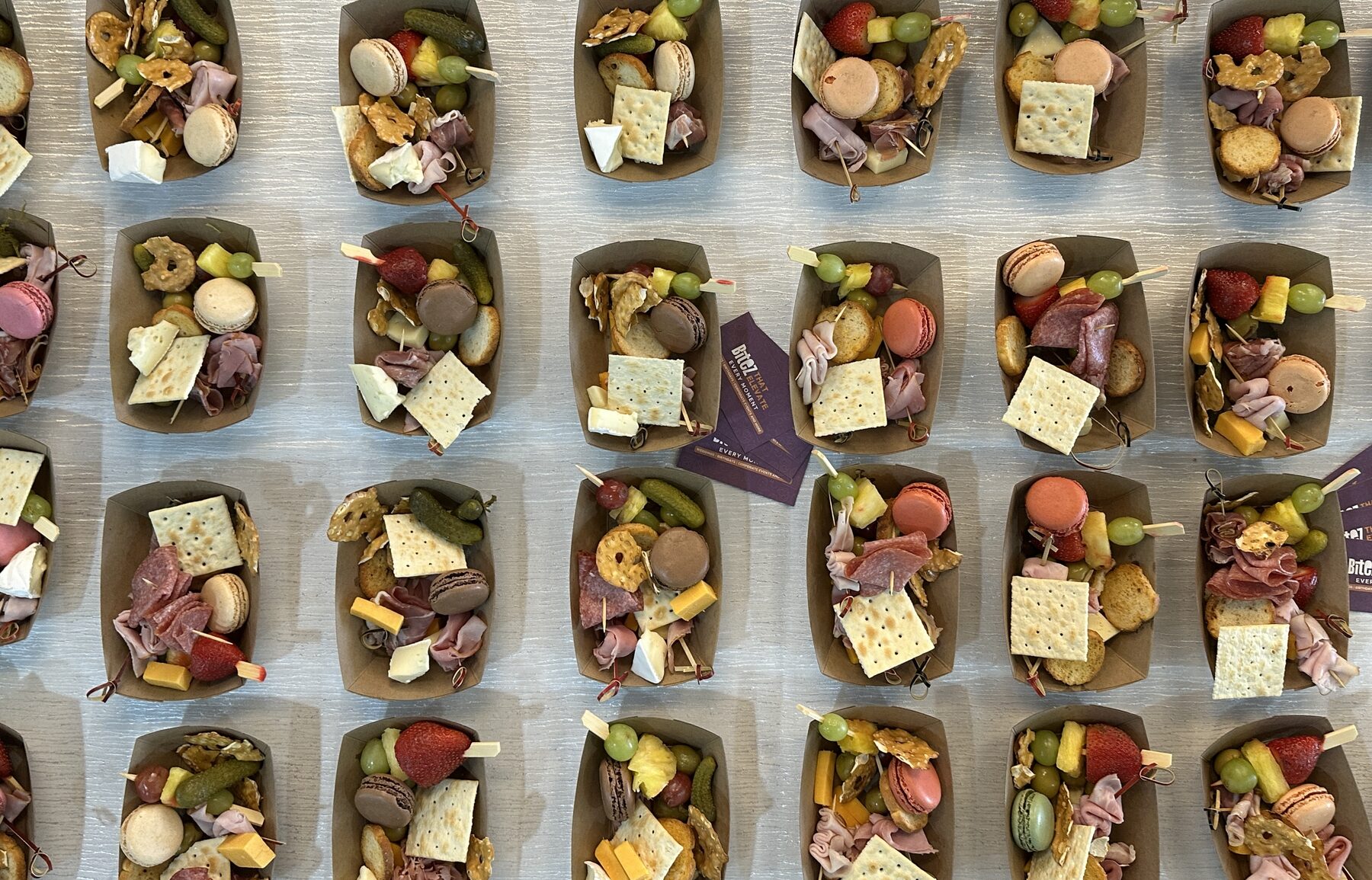 Rows of individual charcuterie boats with 249 Bitez event cards.