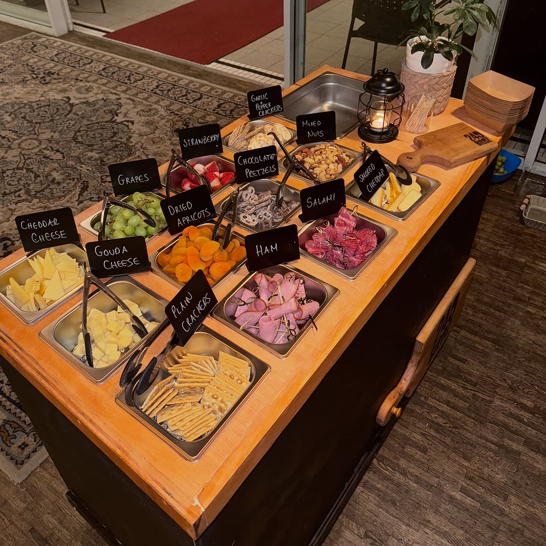 The 249 Bitez charcuterie cart styled at night — chalk labels lit by lantern light.
